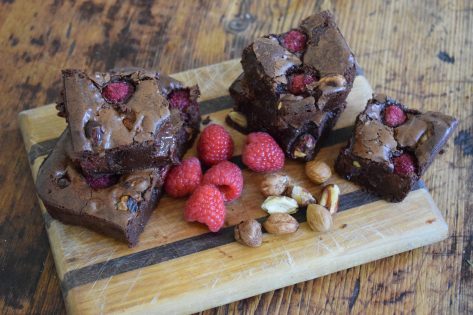 Cobnut and raspberry brownies on wooden board and table